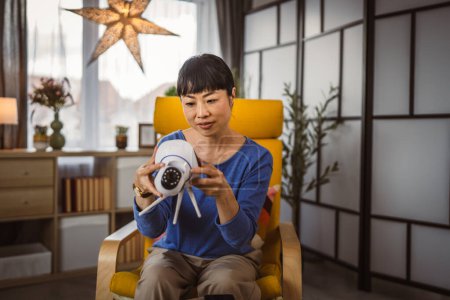 Photo for Mature japanese woman adjust prepare home surveillance security camera - Royalty Free Image