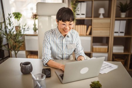 Photo for Mature japanese woman with eyeglasses work on laptop at office - Royalty Free Image