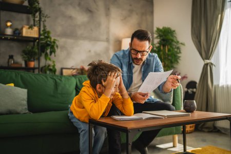 Photo for Exhausted father help son to finish his homework while son have attention deficit disorder and do not want to study anymore - Royalty Free Image