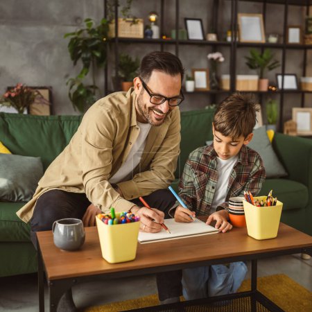 Foto de Padre con anteojos e hijo caucásico dibujar y pintar juntos en casa actividad de ocio - Imagen libre de derechos