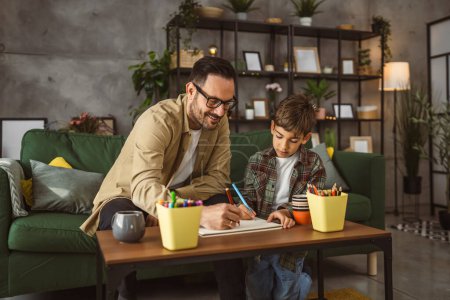 Foto de Padre con anteojos e hijo caucásico dibujar y pintar juntos en casa actividad de ocio - Imagen libre de derechos