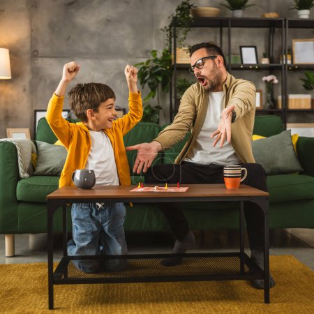 Photo for Father with eyeglasses and son caucasian play board game together and the father is angry cause he is lose - Royalty Free Image