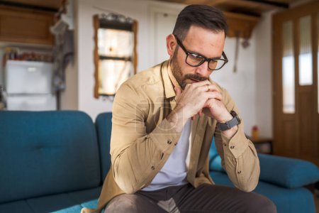 Adult worry man sit on the sofa and think about business decision at home