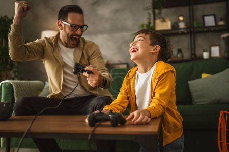 Foto de Padre e hijo caucásico jugar videojuegos con joystick y divertirse en casa feliz disfrutar - Imagen libre de derechos