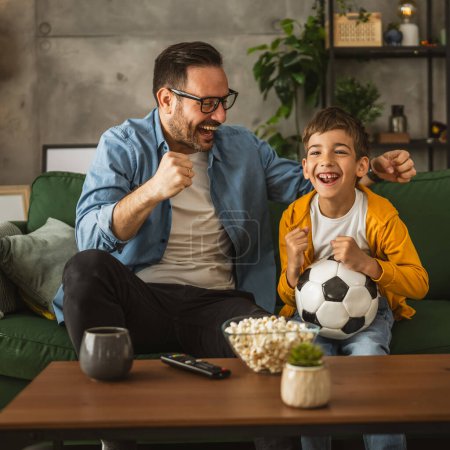 Photo for Father and son caucasian watch football match and cheer at home noisy, excited, happy - Royalty Free Image