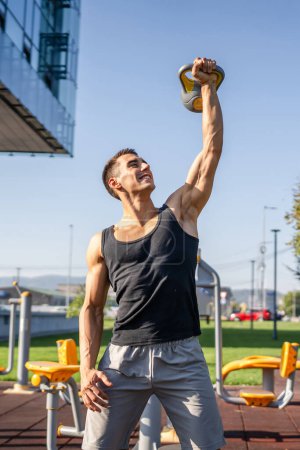 Un homme jeune athlète musculaire masculin caucasien debout en plein air dans l'entraînement de jour avec cloche russe girya kettlebell poids exercice force et conditionnement endurance personne réelle copier l'espace