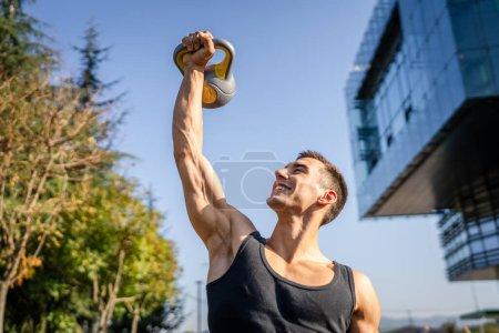 Un homme jeune athlète musculaire masculin caucasien debout en plein air dans l'entraînement de jour avec cloche russe girya kettlebell poids exercice force et conditionnement endurance personne réelle copier l'espace