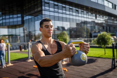 Photo for One man young caucasian male muscular athlete stand outdoor in day training with russian bell girya kettlebell weight exercise strength and conditioning endurance real person copy space - Royalty Free Image