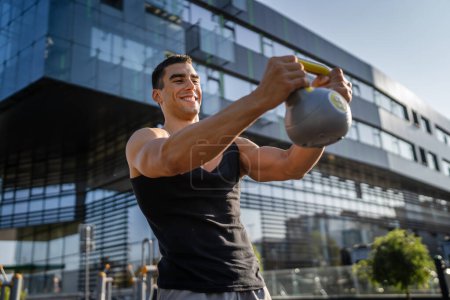 One man young caucasian male muscular athlete stand outdoor in day training with russian bell girya kettlebell weight exercise strength and conditioning endurance real person copy space