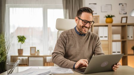 Foto de Adulto hombre de negocios caucásico con gafas se sientan en la oficina mirar el ordenador portátil y leer, pensar en el documento - Imagen libre de derechos