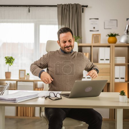 Photo for Exhausted adult man have back or kidney pain while he work at office - Royalty Free Image