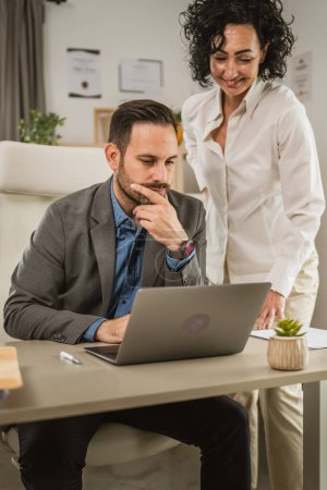Téléchargez les photos : Two colleagues man and woman work together on laptop at office - en image libre de droit