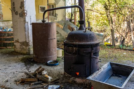 Photo for Distillation pot, a key element in the process of crafting alcoholic beverages, sits in a humble rural yard. This evokes the traditional method of preparing spirits in a rustic setting - Royalty Free Image