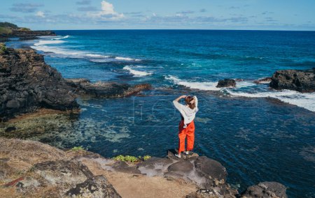 Lonely woman dressed light summer clothes enjoying Indian ocean view with strong surf on cliff at Gris Gris viewpoint extreme south of Mauritius island. Traveling around the world concept image.