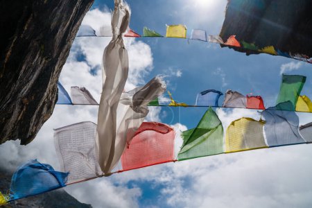 Foto de Banderas sagradas budistas orando multicolores con mantras ondeando y agitando el fuerte viento con cielo azul con fondo de nubes blancas. Parque Nacional Makalu Barun, ruta de escalada pico Mera, Nepal - Imagen libre de derechos