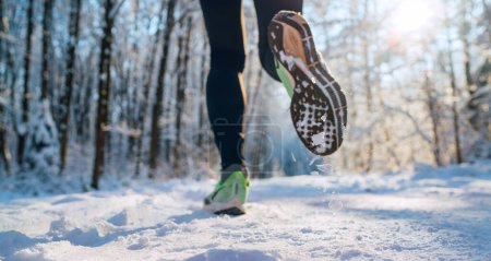 Chaussures de course semelle close up image des pieds de jogger d'hiver dans les baskets de course sur le sentier du parc enneigé pendant la journée ensoleillée. Vue arrière prise de vue unique.