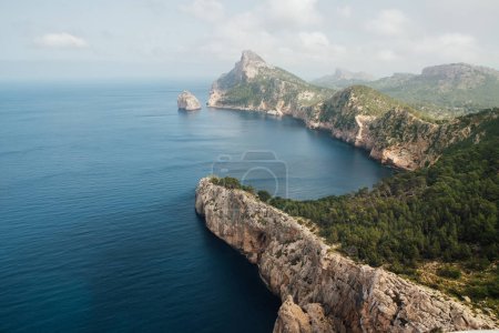 Beautiful Mallorca rocky coast covered with green forest. Balearic Sea as a part of Mediterranean Sea washing Es Colomer cape aerial view. Mallorca island, Balearic Islands, Spain.