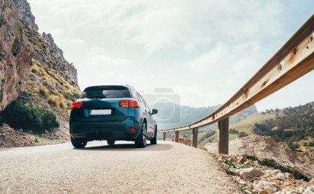 Fast-moving compact auto on the mountain road asphalt road with steel Traffic Guardrail.  Traveling on Mallorca island in Spain, renting car or safety on the roads concept image.