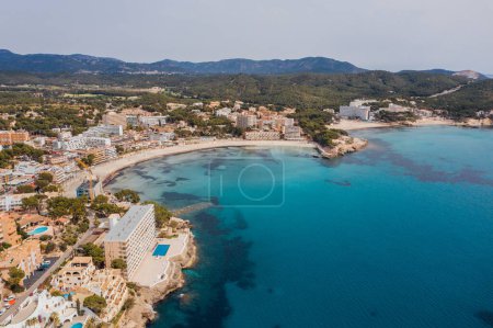 Beautiful aerial drone view shot of Peguera town on rocky Mediterranean cliff coast with cozy tranquil turquoise bays washed with sea waves. Traveling and Balearic Islands vacation concept