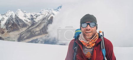 Cheerful laughing climber in sunglasses portrait with backpack ascending Mera peak high slopes at 6000m enjoying legendary Mount Everest, Nuptse, Lhotse with South Face wall beautiful High Himalayas.
