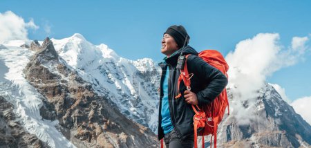 Porträt eines lächelnden Sherpa-Mannes mit Rucksack, der Bergblick und frische Luft mit dem 6476m hohen Mera-Gipfel genießt. Himalaya-Expedition während der Bergbesteigung. Reise- und Aktiv-Konzept
