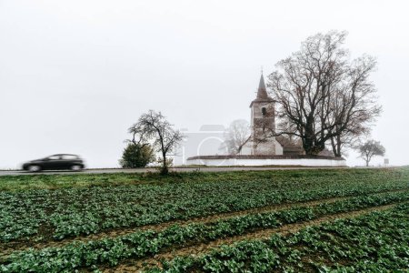 Photo for Rural country with blurred car motion and old gothic church in Ludrova village in Slovakia. - Royalty Free Image