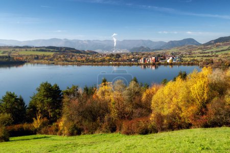 Photo for Colorful autumn landscape with lake Liptovska Mara, yellow trees and Low Tatras mountains and city Ruzomberok at background. Slovakia. - Royalty Free Image