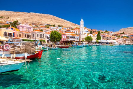 Foto de Halki, Grecia - 6 de julio de 2022: Casas coloridas y barcos de pesca en la pintoresca isla pequeña Halki (Chalki) en Grecia - Imagen libre de derechos