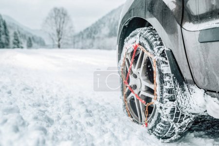 Snow chains on tire of car. Detail of wheel on winter road