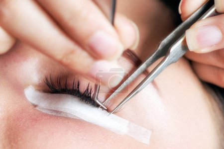 Foto de Beautician making artificial lashes. eyelash extension procedure in a beauty salom - Imagen libre de derechos
