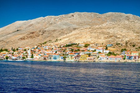 Foto de Halki, Grecia - 6 de julio de 2022: Casas coloridas en la pequeña isla pintoresca Halki en el mar Egeo, parte de las islas del Dodecaneso en Grecia - Imagen libre de derechos