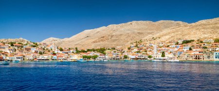 Foto de Halki, Grecia - 6 de julio de 2022: Casas coloridas en la pequeña isla pintoresca Halki (Chalki) en el mar Egeo, parte de las islas del Dodecaneso en Grecia - Imagen libre de derechos