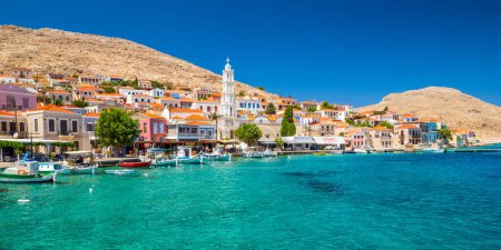 Foto de Halki, Grecia - 6 de julio de 2022: Pueblo pesquero con casas coloridas en la isla de Halki en Grecia - Imagen libre de derechos