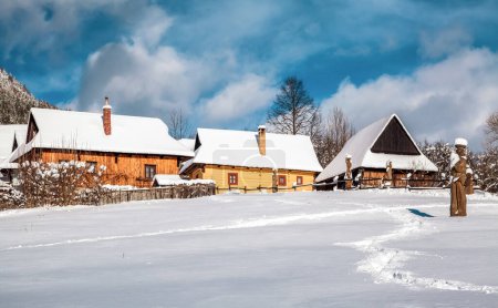 Foto de VLKOLINEC, ESLOVAQUIA - 31 DE ENERO DE 2015: Casa de campo de madera cubierta de nieve en la aldea Vlkolinec, Eslovaquia - Imagen libre de derechos