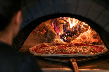 Téléchargez les photos : Concept de nourriture. Préparation de pizza italienne traditionnelle. Pizza cuite au four devant le four
.. - en image libre de droit