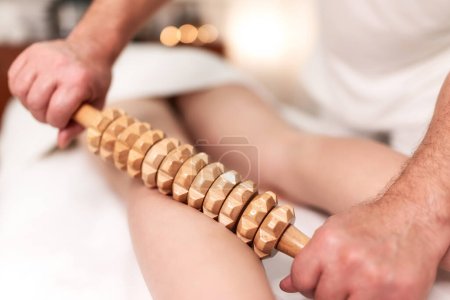Rolling pin madero therapy massage. Female masseuse performing cellulite reduction treatment.