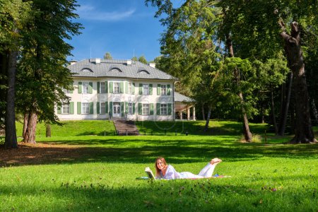 Photo for Happy girl lying on a blanket in park in front of manor house in Oscadnica, Slovakia - Royalty Free Image