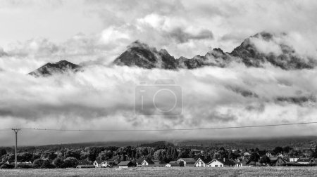Téléchargez les photos : Maisons dans village et grandes montagnes dans les nuages en arrière-plan. Hautes montagnes Tatras en SLovakia - en image libre de droit