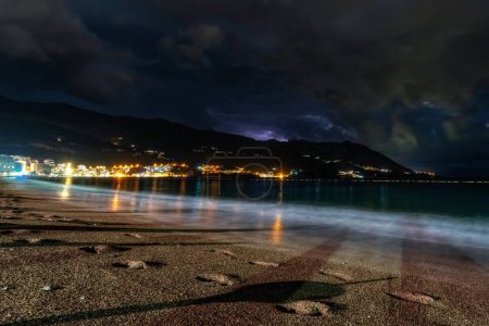 Cielo nocturno sobre el mar Adriático y la playa de arena en el complejo Becici en Montenegro.