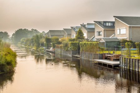 Photo for Homes on water edge in residential area in the Netherlands. Under hazy conditions. - Royalty Free Image