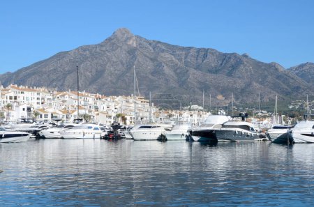 Téléchargez les photos : Marbella, Espagne - 10 décembre 2023 : Bateaux blancs et maisons à Port Banus au pied de la montagne à Marbella, Andalousie, Espagne. - en image libre de droit
