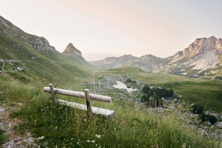 Photo for Wooden bench overlooking a majestic mountain vista invites peaceful contemplation. The setting sun casts a warm glow over the rugged landscape, promising adventure - Royalty Free Image