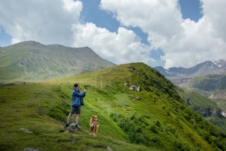 An explorer captures the essence of the mountains, accompanied by a loyal Nova Scotia Duck Tolling Retriever dog