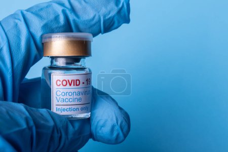 Foto de Mano con guante médico que sostiene la vacuna contra el coronavirus COVID-19. Copiar espacio - Imagen libre de derechos