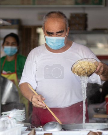 Photo for Kota Kinabalu, Sabah, Malaysia-August 7, 2021 : Local lifestyle food vendor with medical face mask during preparing food to Prevention of bacterial infection Corona virus or Covid-19 - Royalty Free Image