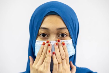 Foto de Primer plano retrato de atractivo contenido serio muslimah usando azul pastel hijab mascarilla blanca aislada sobre fondo blanco - Imagen libre de derechos