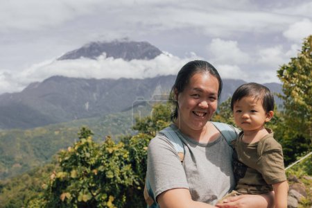 Portraitbild der asiatischen chinesischen Mutter mit glücklichen 1-2 Jahren mit dem größten Berg Kinabalu von Sabah, Borneo mit klarem blauem Himmel