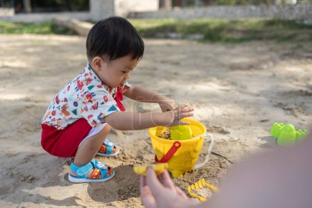 Foto de Un niño chino asiático en la playa en los juguetes para la arena. Juegos infantiles. Juegos en la playa - Imagen libre de derechos