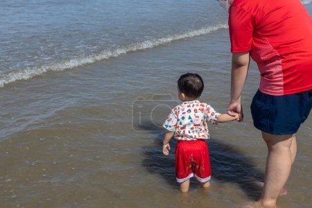 Téléchargez les photos : Joyeux petit garçon passer un bon moment à la plage et courir à la plage - en image libre de droit