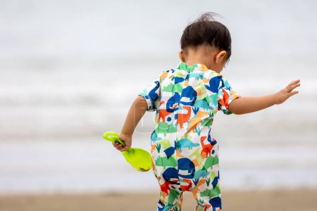 Foto de Un bebé chino asiático en la playa con los juguetes para la arena. Juegos infantiles. Juegos en la playa - Imagen libre de derechos